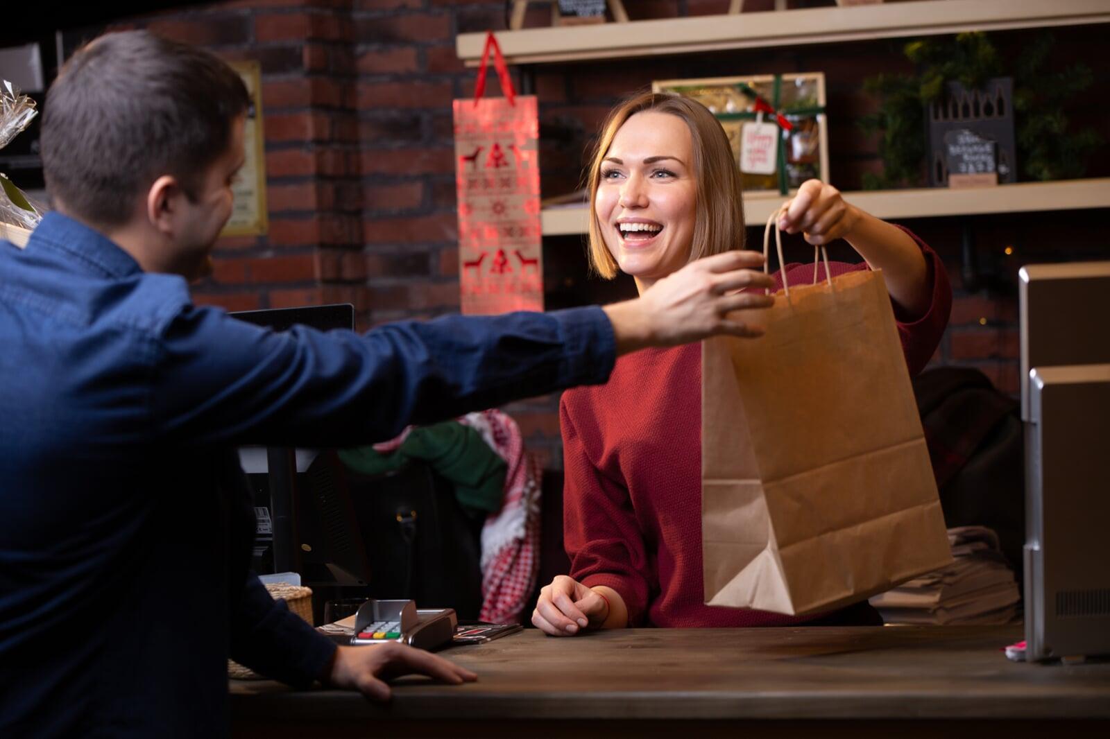 Cashier smiles and hands over bag